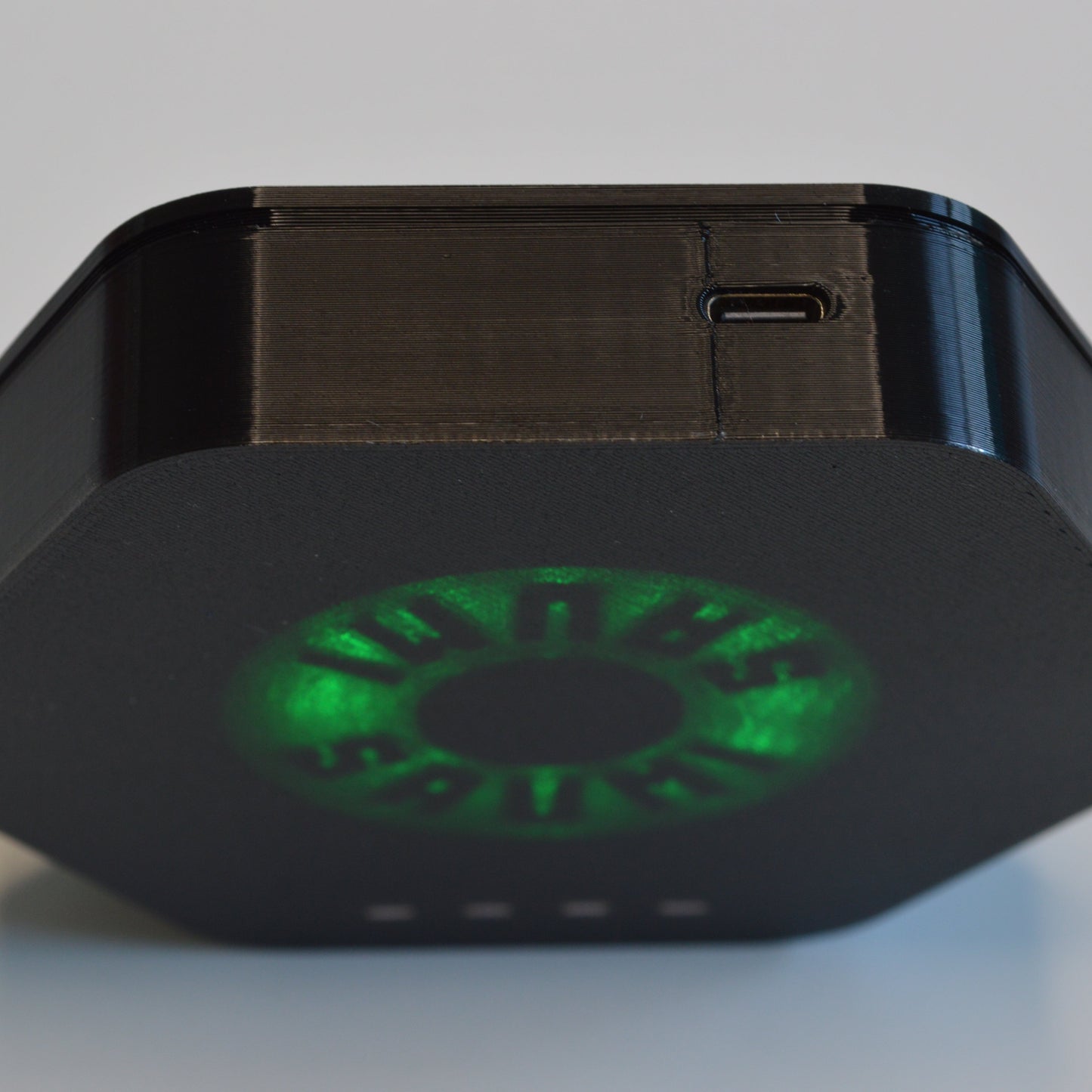 Black electronic device with green LED on a light gray background