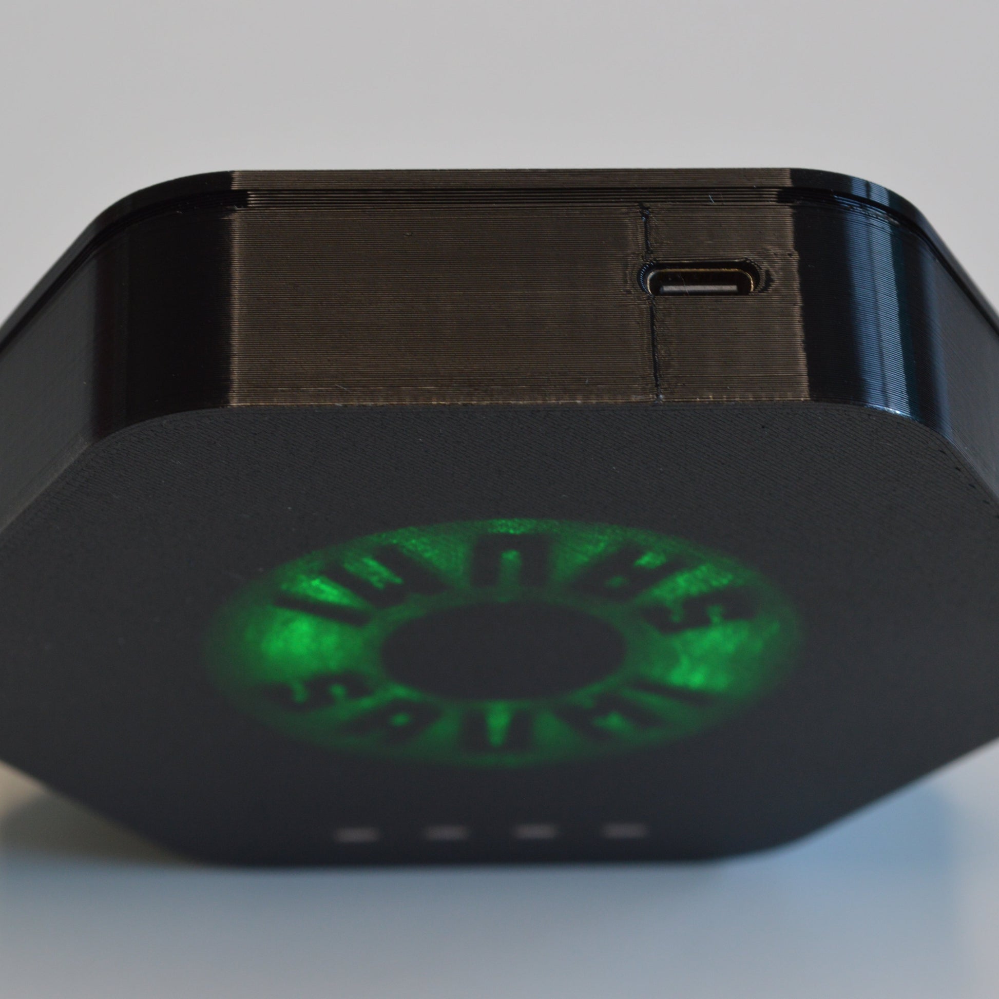 Black electronic device with green LED on a light gray background